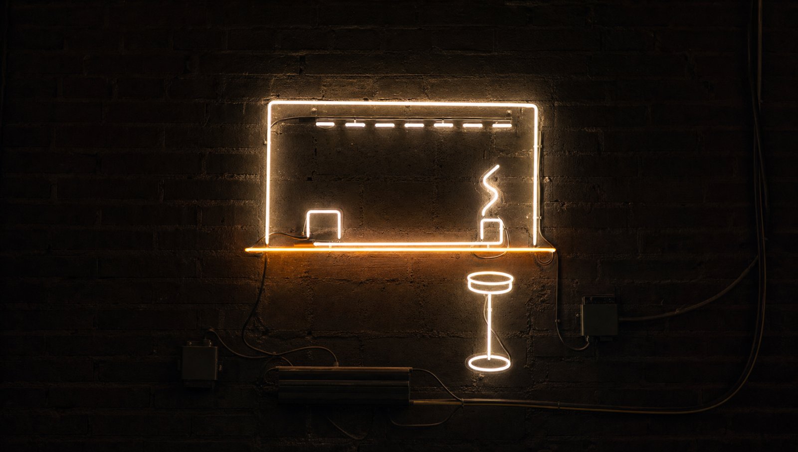 The service hatch as bent-glass neon linework on dark brick