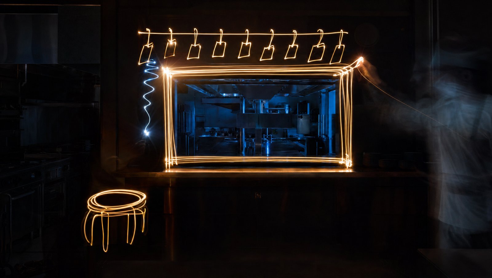 The service hatch drawn in long-exposure light painting inside a dark kitchen